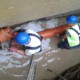 Two men in hard hats and safety vests working on a pipe.